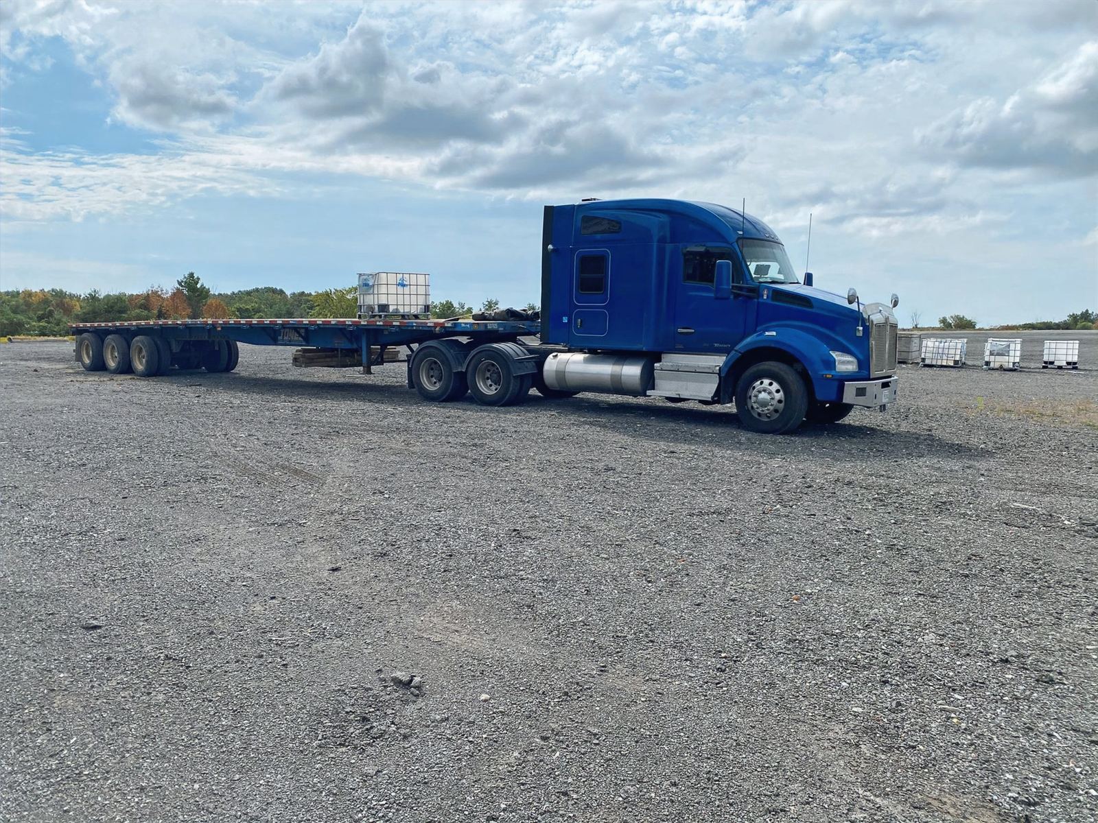 Blue Novalight tractor with an empty flatbed trailer