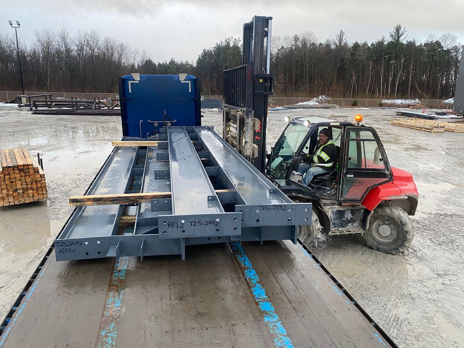 Forklift loading steel components onto a Novalight specialized trailer
