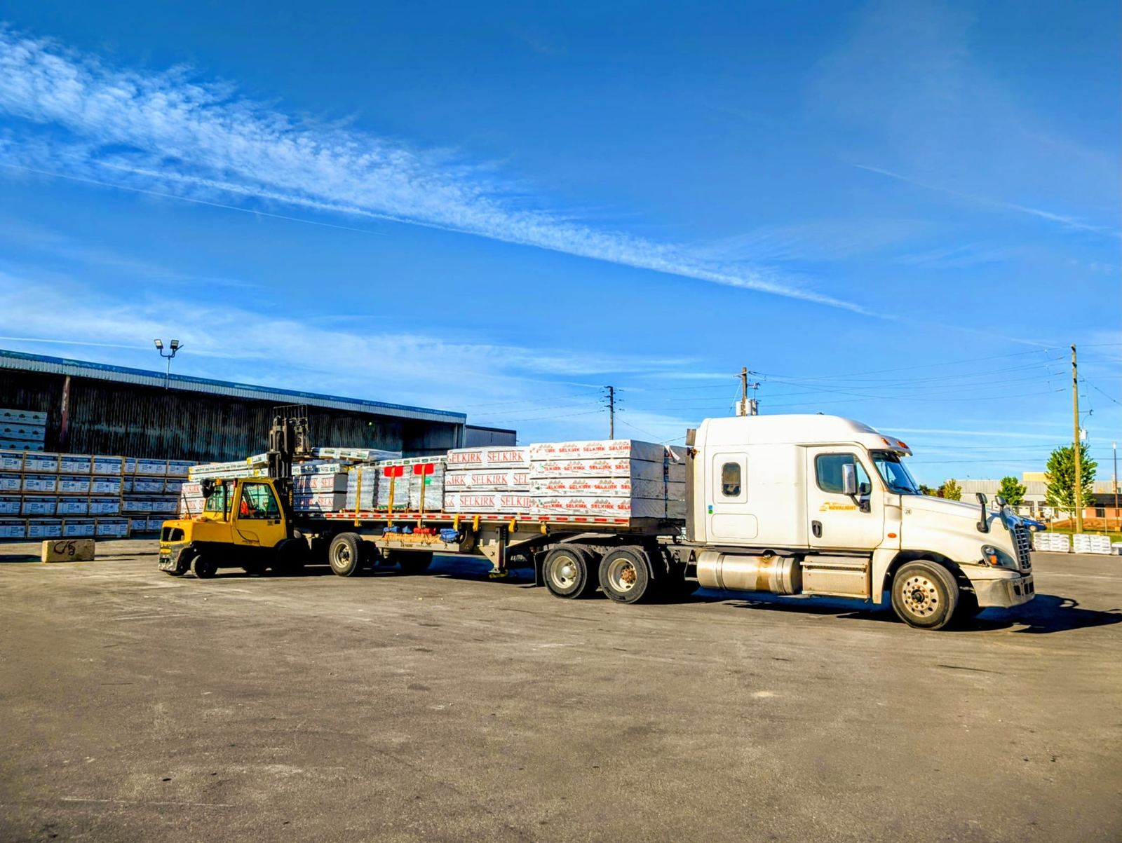 Forklift loading materials onto a white Novalight truck